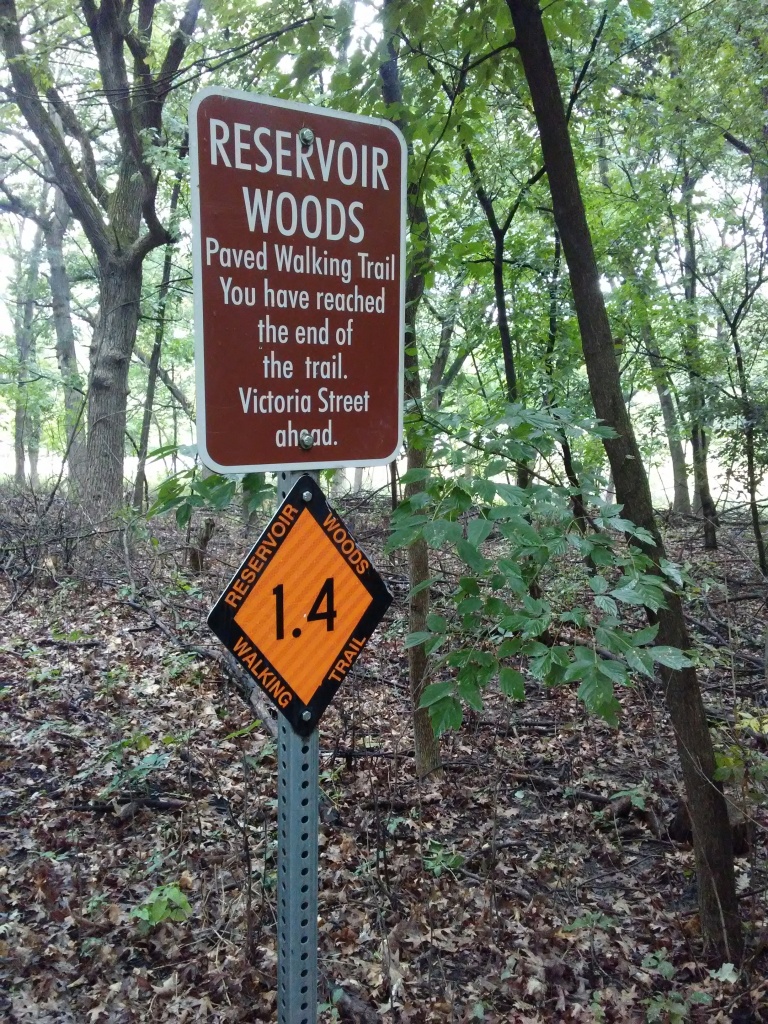 Woods. orange diamond shaped sign "1.4". and brown rectangular sign that says it is the end of the trail.